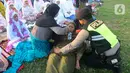 Anggota polisi dari Polda Bali membantu warga yang pingsan saat melakukan shalat Idul Fitri di Lapangan Pegok, Sesetan, Denpasar, Sabtu (22/4/2023). (merdeka.com/Arie Basuki)