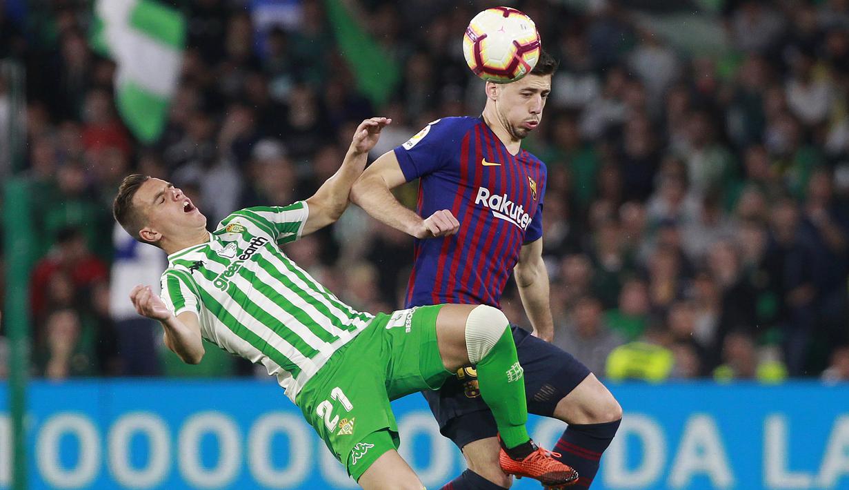 Bek Barcelona, Lenglet, berebut bola dengan pemain Real Betis, Lo Celso, pada laga La Liga 2019 di Stadion Benito Villamarin, Minggu (17/3). Barcelona menang 4-1 atas Real Betis. (AP/Miguel Morenatti)