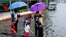 Sejumlah anak-anak membantu warga menyebrangi genangan air di Manila, Filipina, Kamis (27/7). PAGASA mengatakan bahwa hembusan angin saat badai terjadi dengan kecepatan maksimum 85 kilometer per jam (53 mil per jam). (AP/Bullit Marquez)