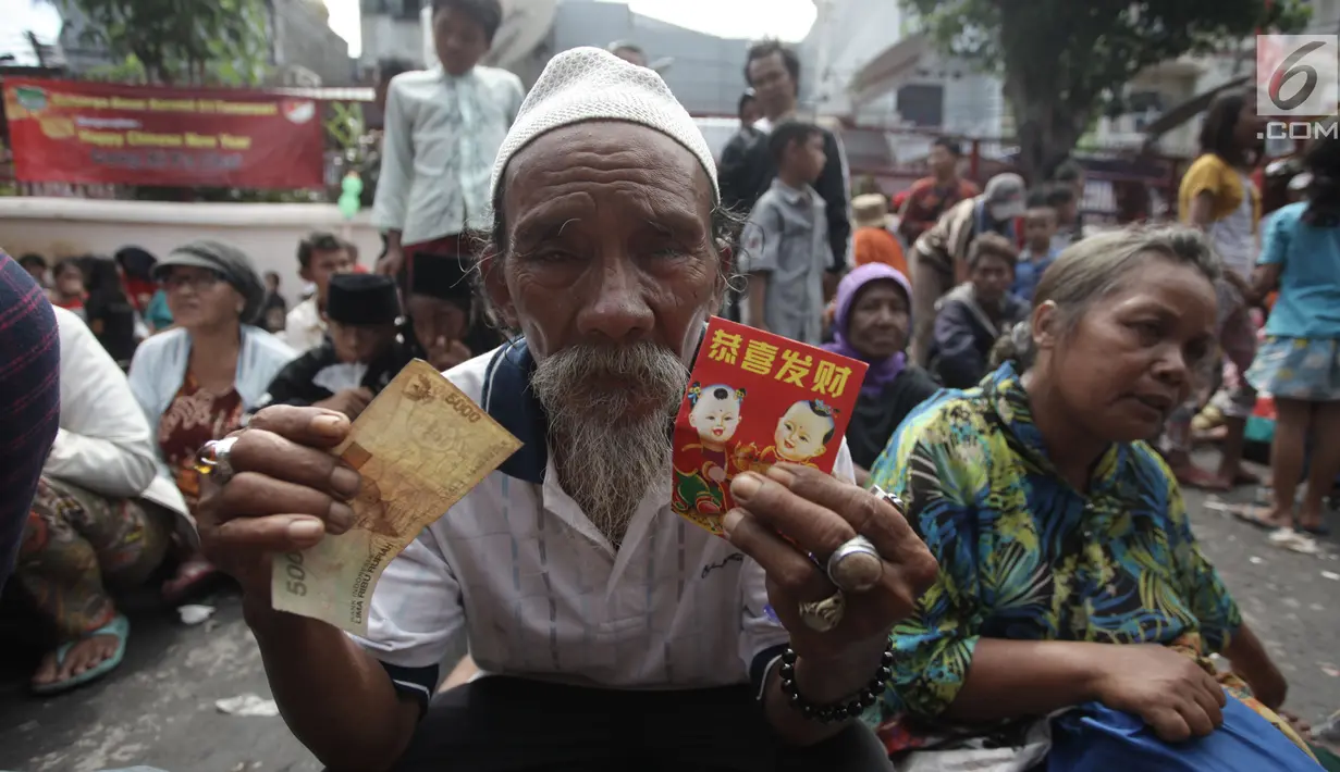 Seorang pengemis menunjukkan angpau yang didapatkan dari warga keturunan Tionghoa di Vihara Dharma Bhakti, Petak Sembilan, Jakarta Barat, Jumat (16/2). Pengemis musiman memadati Vihara Dharma Bhakti pada perayaan Imlek 2018. (Liputan6.com/Arya Manggala)