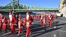 Orang-orang dengan kostum Sinterklas ikut serta dalam lomba lari tradisional menyambut Natal di tepi Sungai Danube di Budapest, Hungaria, pada 3 Desember 2023. (ATTILA KISBENEDEK/AFP)
