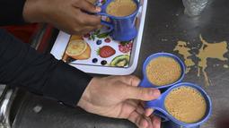 Pramusaji bersiap untuk menyajikan cangkir teh kepada pelanggan di sebuah restoran di Islamabad, Pakistan, Rabu (15/6/2022). Seorang menteri Pakistan mengatakan orang Pakistan dapat mengurangi konsumsi teh mereka menjadi satu atau dua cangkir per hari. Sebab impor teh menambah beban keuangan pada pemerintah. (Aamir QURESHI / AFP)