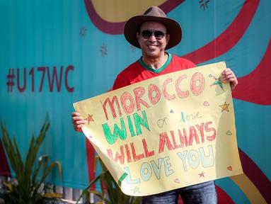 Suporter Maroko, Mohammad Aziz Mrabat berpose dengan membentangkan poster bertuliskan "Maroko, menang atau kalah aku tetap mencintaimu" menjelang laga kedua Grup A Piala Dunia U-17 2023 antara Timnas Maroko U-17 melawan Timnas Ekuador U-17 di Stadion Gelora Bung Tomo (GBT), Surabaya, Senin (14/11/2023). (Bola.com/Bagaskara Lazuardi)