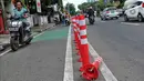 Pengendara bermotor melintas di samping stick cone pembatas jalur sepeda di Kawasan Jalan Penjernihan Jakarta, Sabtu (10/12/2022). Keadaan stick cone untuk pembatas jalur sepeda tersebut terlihat sudah rusak dan tidak terpasang dengan benar. (Liputan6.com/Angga Yuniar)