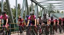 Aksi para pebalap sepeda saat melewati sebuah jembatan di Etape 1 Tour de Singkarak 2015, Sabtu (3/10/2015). (Bola.com/Arief Bagus)