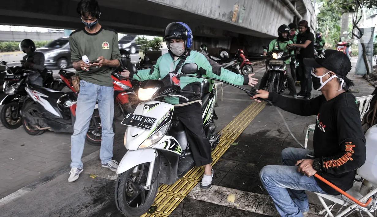 Petugas menyemprotkan cairan disinfektan pada kendaraan pengojek daring saat pemeriksaan rutin di Posko Aman Covid-19, Jakarta, Selasa (11/8/2020). Dalam sehari, Posko Aman Covid-19 rata-rata mampu memeriksa hingga 1.000 pengojek mulai pukul 08.00 WIB-17.00 WIB. (merdeka.com/Iqbal Nugroho)