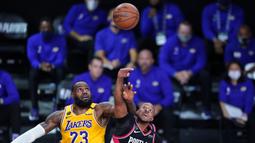 Pebasket Los Angeles Lakers, LeBron James, berebut bola dengan pebasket Portland Trailblazers, CJ McCollum, pada babak pertama playoff NBA 2020 di AdventHealth Arena, Rabu (19/8/2020). LA Lakers takluk 93-100 atas Portland Trailblazers. (AFP/Ashley Landis-Pool/Getty Images)