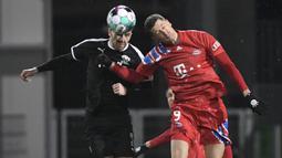 Striker Bayern Munich, Robert Lewandowski (kanan) berduel udara dengan bek tim Divisi 2 Holstein Kiel, Marco Komenda dalam laga babak kedua Piala DFB Pokal 2020/21 di Kiel, Rabu (13/1/2021). Bayern Munich kalah dari Holstein Kiel lewat adu penalti 5-6 (2-2). (AFP/Fabian Bimmer/Pool)