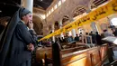 Seorang biarawati menangis sambil berdiri mengamati kondisi Gereja Katedral Koptik di Kairo, Mesir, Minggu (11/12). Ledakan yang menghantam gereja tersebut menewaskan sedikitnya 25 orang dan melukai 49 lainnya. (REUTERS/Amr Abdallah Dalsh)