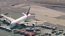 Petugas tanggap darurat berkumpul di luar pesawat setelah sekitar 100 penumpang Emirates Airline dilaporkan sakit di Bandara Kennedy New York, Rabu (5/9). Pesawat dari Dubai ke New York itu dikarantina dan dipantau polisi kontra-terorisme. (WABC 7 via AP)