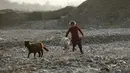 Seorang gadis nomaden Gujjar menggembalakan kambing ketika kelompok mereka berhenti sementara di jalan raya Jammu-Srinagar di Nagrota, di pinggiran Jammu, India, Selasa (9/11/2021). Anggota suku tersebut pindah dari perbukitan untuk menghindari musim dingin. (AP Photo/Channi Anand)