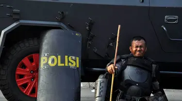 Seorang petugas yang kelelahan bersandar di mobil water cannon yang terparkir di kawasan Patung Kuda, Jakarta, Kamis (21/8/14). (Liputan6.com/Miftahul Hayat)