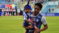 Pemain Arema, Hanif Sjahbandi menggendong satu di antara penderita kanker sebelum pertandingan melawan Persela di Stadion Kanjuruhan, Malang, Sabtu (7/7/2018). (Bola.com/Iwan Setiawan)