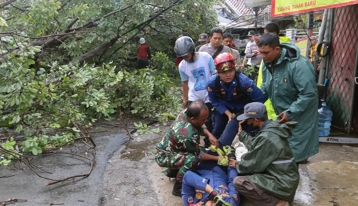 Peristiwa tersebut juga menyebabkan salah satu personel pemadam dan penyelamat mengalami kecelakaan saat kerja saat berupaya memotong pohon tersebut. (merdeka.com/Arie Basuki)