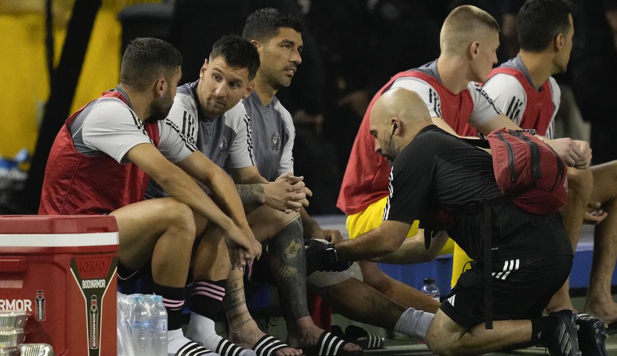 Pemain Inter Miami, Luis Suarez (tengah) mendapatkan perawatan di samping Lionel Messi yang sedang berbicang dengan Jordi Alba pada laga persahabatan melawan Timnas El Salvador yang digelar di Kota San Salvador, El Salvador, Sabtu (20/01/2024) pagi WIB. (AP Photo/Moises Castillo)