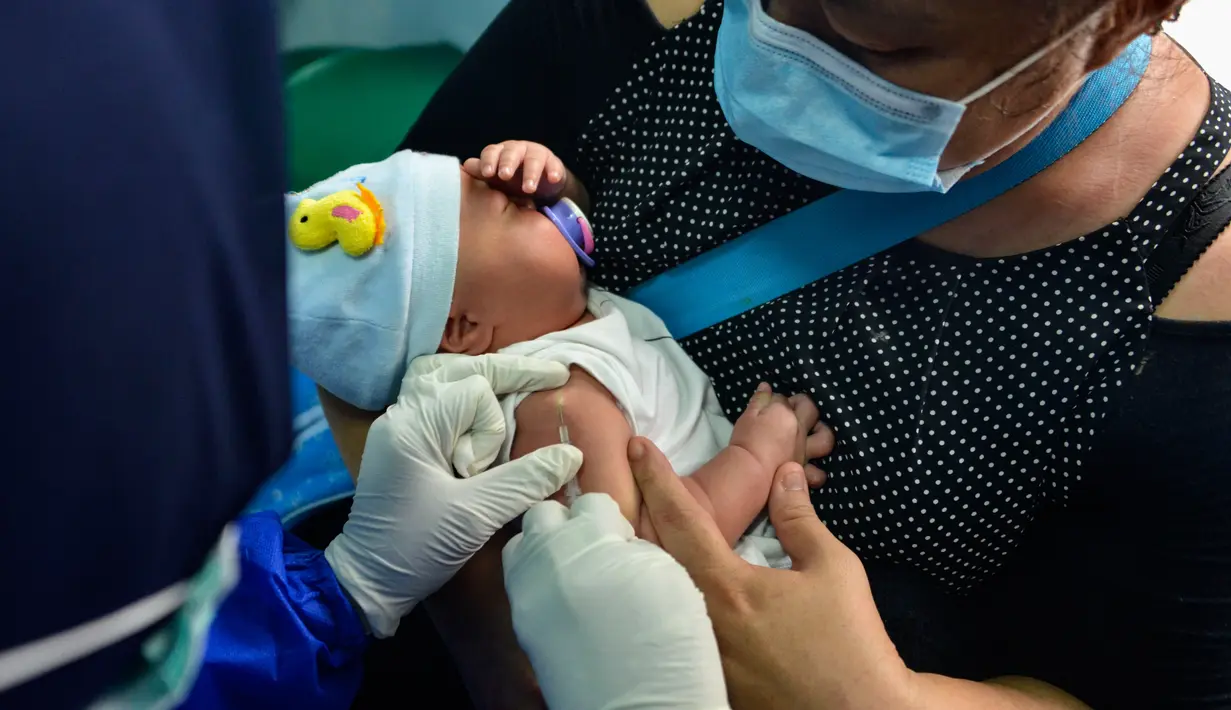 Seorang ibu menggendong bayinya saat petugas kesehatan menyutikkan vaksin untuk tuberkulosis di sebuah Pukesmas di Banda Aceh, Aceh, Senin (15/6/2020). Memasuki tatanan normal baru, pelayanan imunisasi anak kembali dibuka setelah sebelumnya sempat terhenti akibat COVID-19. (CHAIDEER MAHYUDDIN/AFP)