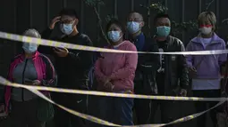 Warga berbaris di belakang pita peringatan untuk mendapatkan swab tenggorokan COVID-19 rutin mereka di tempat pengujian virus corona di Beijing, Kamis (6/10/2022). Xinjiang yang luas adalah wilayah China terbaru yang terkena pembatasan perjalanan COVID-19, karena China semakin meningkatkan langkah-langkah pengendalian menjelang kongres penting Partai Komunis akhir bulan ini. (AP Photo/Andy Wong)