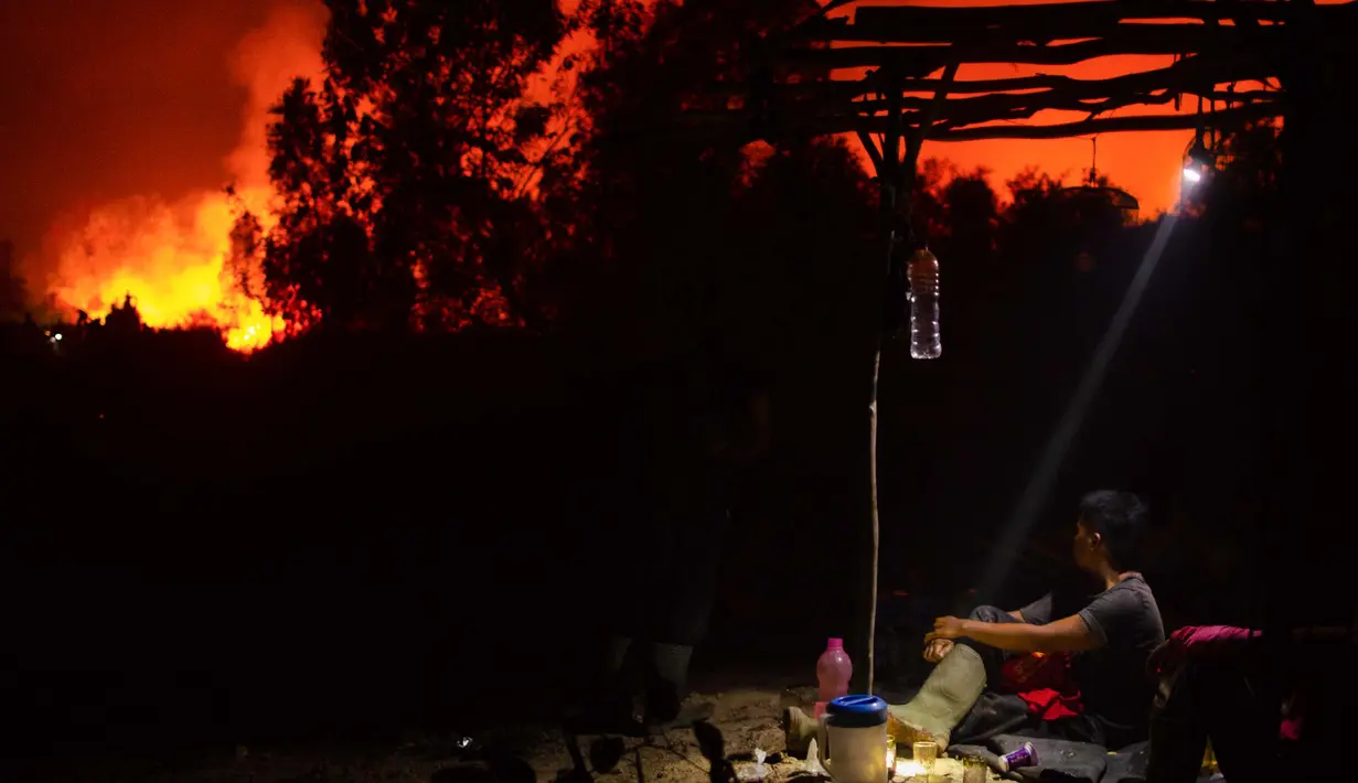 Dalam foto yang diambil pada tanggal 10 Oktober 2023 ini, seorang pria memantau kebakaran hutan di luar rumah kerabatnya ketika api mendekat di Ogan Ilir, Sumatra Selatan. (Al ZULKIFLI/AFP)