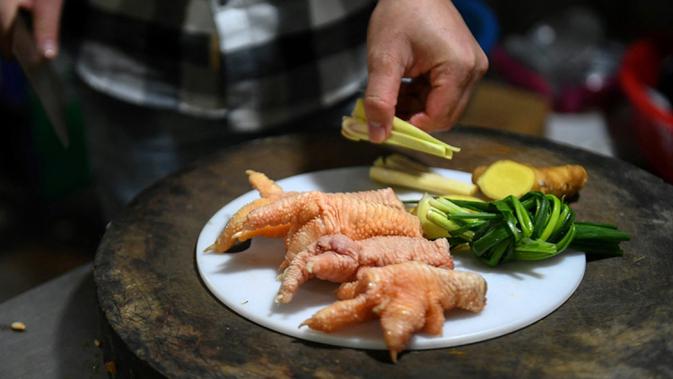 Seorang koki sedang menyiapkan ceker ayam Dong Tao di sebuah restoran di Hanoi, Vietnam, 15 Januari 2023. Awalnya daging dari ayam ini dikembangbiakkan secara eksklusif sehingga hanya bisa dikonsumsi oleh keluarga kerajaan saja. (Nhac NGUYEN/AFP)