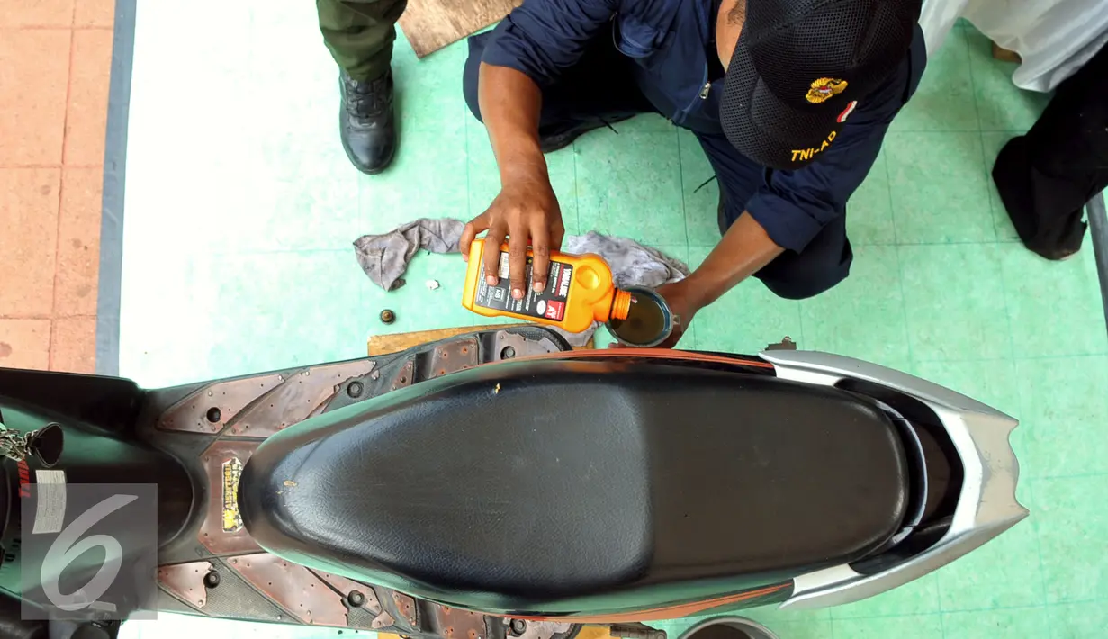 Anggota TNI memasukan oli kedalam motor saat service gratis di kawasan Lapangan Banteng, Jakarta, Jumat (11/12). Kegiatan ini memperingati Hari Juang Kartika Tahun 2015 dan berlangsung sampai hari Minggu (13/12). (Liputan6.com/Faisal R Syam)