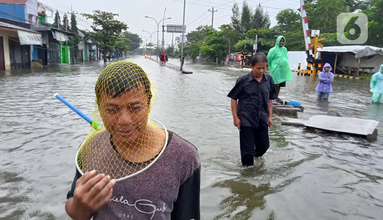 Aktivitas warga saat banjir menggenangi daerah Kaligawe, Kota Semarang, Selasa (9/2/2021). Banjir yang menggenangi daerah Kaligawe sejak beberapa hari lalu hingga Selasa (9/2) pagi masih belum surut dan mengakibatkan mobilitas warga menjadi terhambat. (Liputan6.com/Gholib)