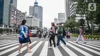 Pejalan kaki menyeberang jalan di kawasan Sudirman, Jakarta Pusat, Rabu (6/1/2021). Pemerintah memberlakukan kebijakan pembatasan sosial berskala besar (PSBB) di wilayah Jawa dan Bali mulai 11 hingga 25 Januari 2021 menyusul lonjakan kasus Covid-19 di sejumlah daerah. (Liputan6.com/Faizal Fanani)