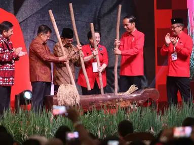 Presiden Jokowi , Wapres Jusuf Kalla, Presiden ke-3 BJ Habibie dan Ketum PDIP Megawati Soekarnoputri menumbuk padi saat acara Rakornas Tiga Pilar PDI P di ICE BSD, Tangerang Selatan, Sabtu (16/12). (Liputan6.com/Angga Yuniar)
