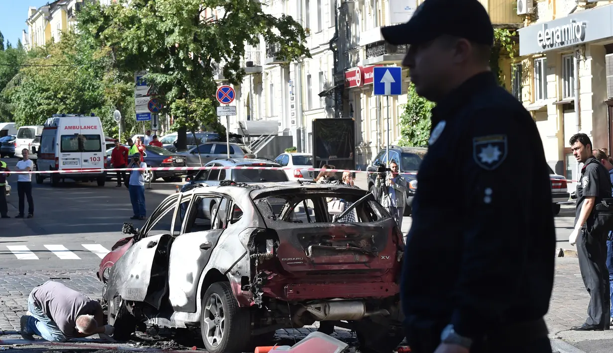 Petugas berdiri dekat mobil yang ditumpangi jurnalis investigasi ternama, Pavel Sheremet yang tewas di Kiev, Ukraina, Rabu (20/7). Jurnalis Ukrayina Pravda itu sedang mengendarai mobil ke tempat kerja ketika mobil tersebut meledak. (Sergei SUPINSKY/AFP)