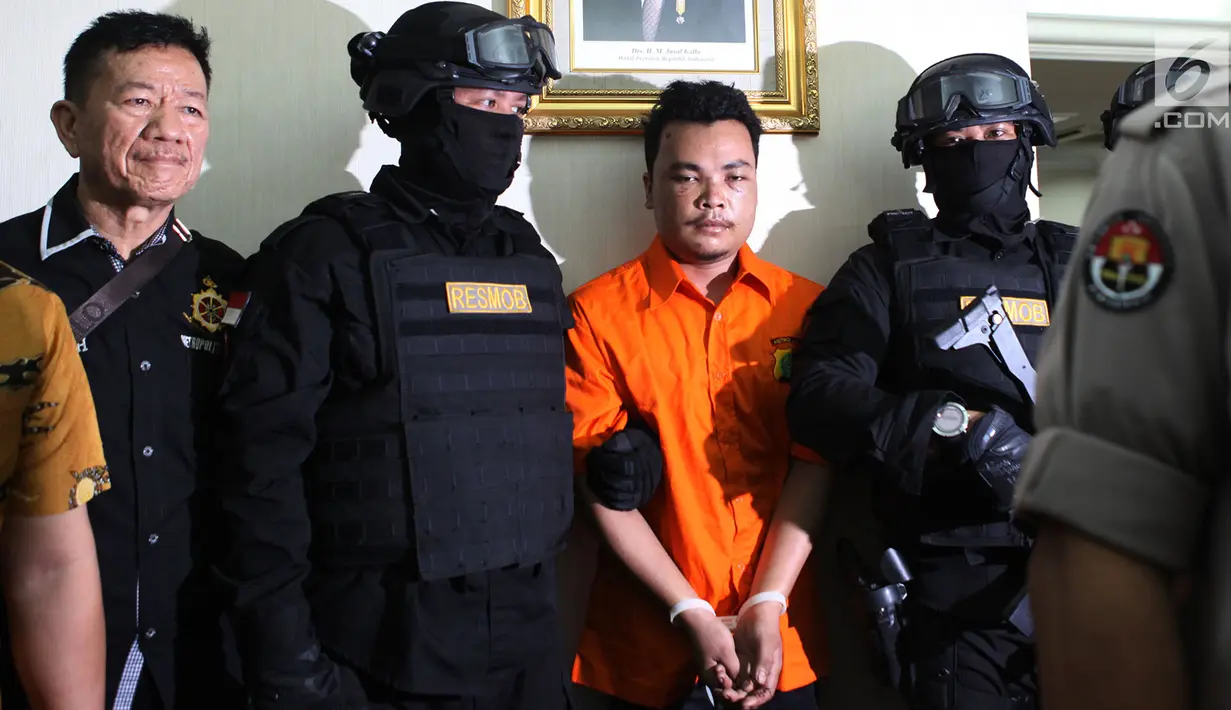 Polisi mengawal tersangka pembunuhan satu keluarga di Kota Bekasi saat gelar perkara di Polda Metro Jaya, Jakarta, Jumat (16/11). Tersangka HS mengaku telah melakukan pembunuhan tersebut. (Merdeka.com/Imam Buhori)