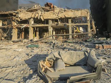 Seorang pria berjalan melewati bangunan yang hancur dan rusak di lokasi serangan udara Israel semalam yang menargetkan pinggiran selatan Beirut pada 27 Oktober 2024. (Foto oleh AFP)