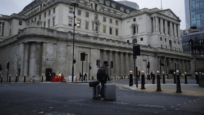Seorang pria berjalan membawa koper melewati Bank of England pada pagi pertama penerapan lockdown nasional ketiga di Kota London, Inggris, 5 Januari 2021. Inggris menerapkan lockdown nasional ketiga untuk membendung lonjakan infeksi COVID-19 yang mengancam rumah sakit. (AP Photo/Matt Dunham)