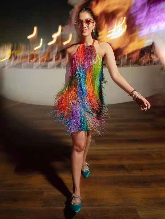 Masih di malam yang sama, Radhika kenakan gaun multiwarna yang cerah. Ia mengenakan gaun halterneck manik-manik karya Ashish Gupta [@shereenlovebug]