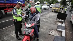 Anggota Polantas menilang pengendara motor yang melintas di jalur cepat di jalan Letjen Suprapto, Jakarta, Selasa (7/11). Sejauh ini, total ada 55.457 kendaraan yang telah ditilang oleh polisi. (Liputan6.com/Faizal Fanani)