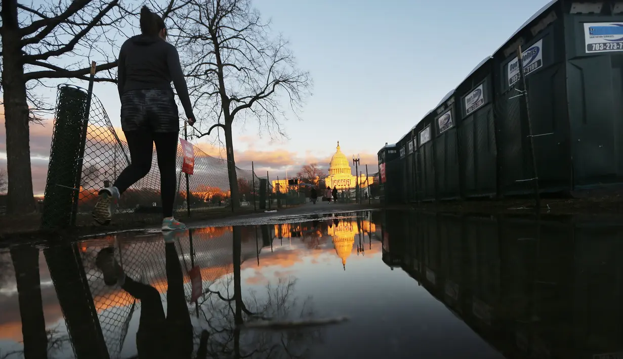Pejalan kaki melintas dekat toilet portable di sekitar Gedung Capitol, Washington DC, Kamis (19/1). Donald Trump tinggal menghitung jam untuk menduduki kursi kepresidenan di Gedung Putih menggantikan Barack Obama. (Mario Tama/Getty Images/AFP)