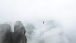 Seorang peserta berjalan diatas tali untuk menyebrangi tebing tinggi di Provinsi Zhejiang , China , 7 Mei 2016. Hanya dengan seutas tali di kaki, mereka berlomba untuk menyebrangi tebing tersebut. (China Daily /REUTERS)
