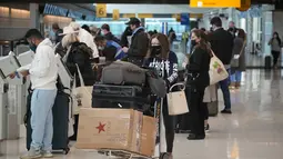 Wisatawan mengantre di kios check-in United American Airlines di terminal Bandara Internasional Denver di Denver (26/12/2021). Maskapai menunda ratusan penerbangan pada Minggu (26/12), karena alasan keterbatasan petugas terkait Covid-19 menambah masalah perjalanan usai Natal. (AP Photo/David Zalubow