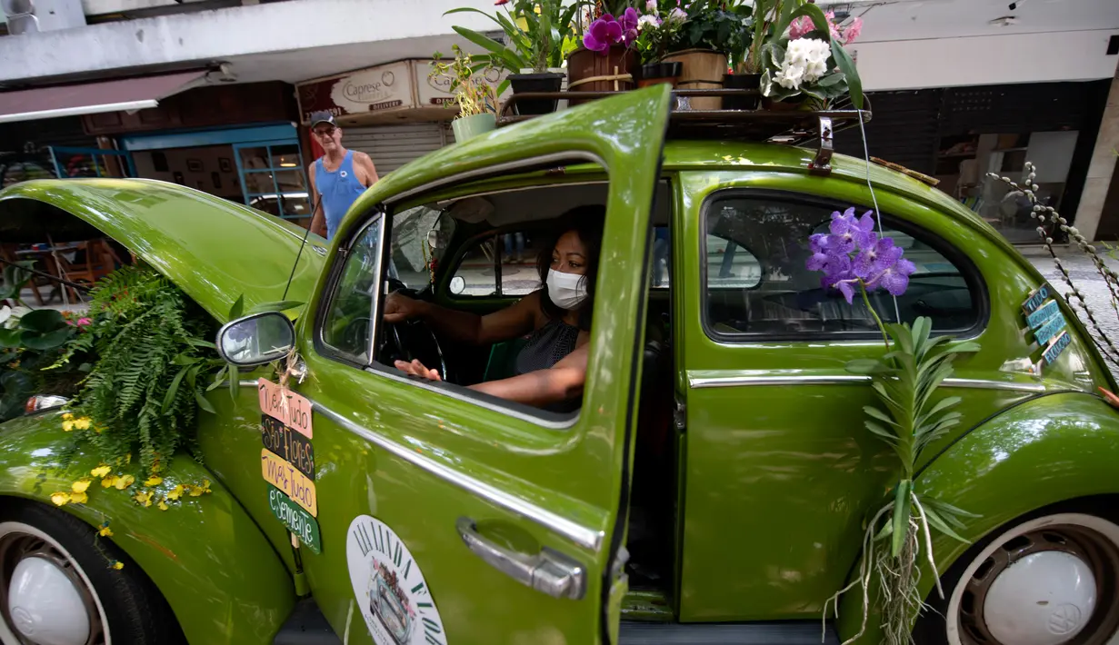 Roberta Machado dari Brasil duduk di Volkswagen Beetle 1969 miliknya yang diubah menjadi toko bunga keliling di Copacabana, Rio de Janeiro, Rabu (14/10/2020). Perempuan 51 tahun ini mengubah VW kodok untuk bertahan dari krisis akibat pandemi COVID-19. (MAURO PIMENTEL/AFP)
