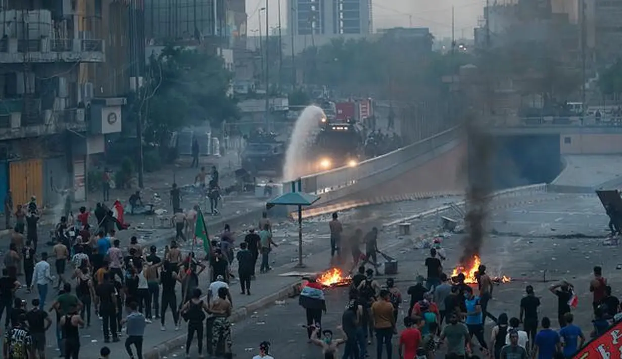 Pengunjuk rasa antipemerintah membakar sejumlah benda dan memblokir jalan saat menggelar protes di Baghdad, Irak, Rabu (2/10/2019). Aksi protes di seluruh Irak telah menewaskan sembilan orang dalam 24 jam. (AP Photo/Hadi Mizban)