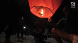 Pengunjung menyalakan api sebelum menerbangkan lampion saat perayaan Tahun Baru Imlek di Pantai Lagoon, Ancol, Jakarta, Selasa (5/2) malam. Sebanyak 500 lampion dilepas dalam  rangka menutup Festival Imlek di Ancol. (Merdeka.com/Iqbal S Nugroho)