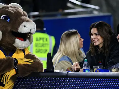 Model Kendall Jenner bercanda dengan Maskot Los Angeles Rams selama paruh kedua pertandingan Los Angeles Rams dan Baltimore Ravens di Los Angeles Memorial Coliseum, California (25/11/2019). Kendall Jenner tampil cantik mengenakan jaket hitam dengan rambut terurai. (Sean M. Haffey/Getty Images/AFP)