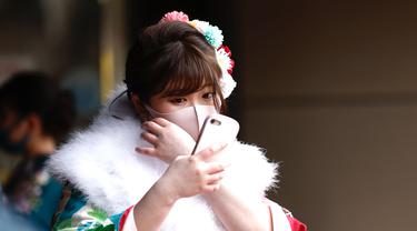 Seorang wanita berusia 20 tahun mengenakan kimono menunggu di pintu masuk Todoroki Arena untuk menghadiri upacara perayaan "Coming-of-Age Day" di Kawasaki, prefektur Kanagawa (11/1/2021). Acara ini digelar dalam keadaan darurat karena Covid-19 pandemi virus corona. (AFP/Behrouz Mehri)