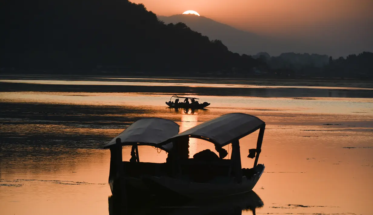 Nelayan menunggu di perahu kecil setelah memancing di Danau Dal saat matahari terbenam di Srinagar (9/9/2019). Danau terbesar kedua di propinsi Jammu dan Kashmir ini  merupakan pusat pariwisata dan rekreasi. (AFP Photo/Tauseef Mustafa)