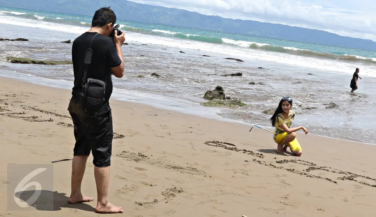 Warga mengabadikan gambar di pinggir Pantai Karang Hawu, Sukabumi, Jawa Barat, (8/2). Mengisi libur Imlek, Sejumlah wisatawan mengunjungi Pantai Karang Hawu. (Liputan6.com/Immanuel Antonius)