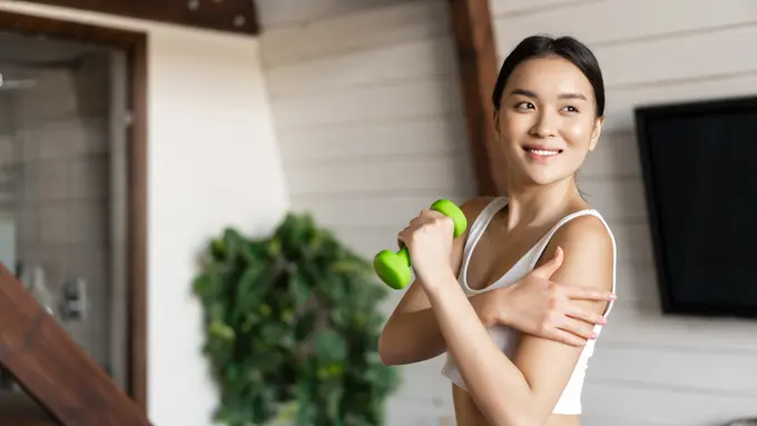 Seorang perempuan sedang berolahraga dengan mengangkat beban (Foto Dok: Freepik/benzoix)