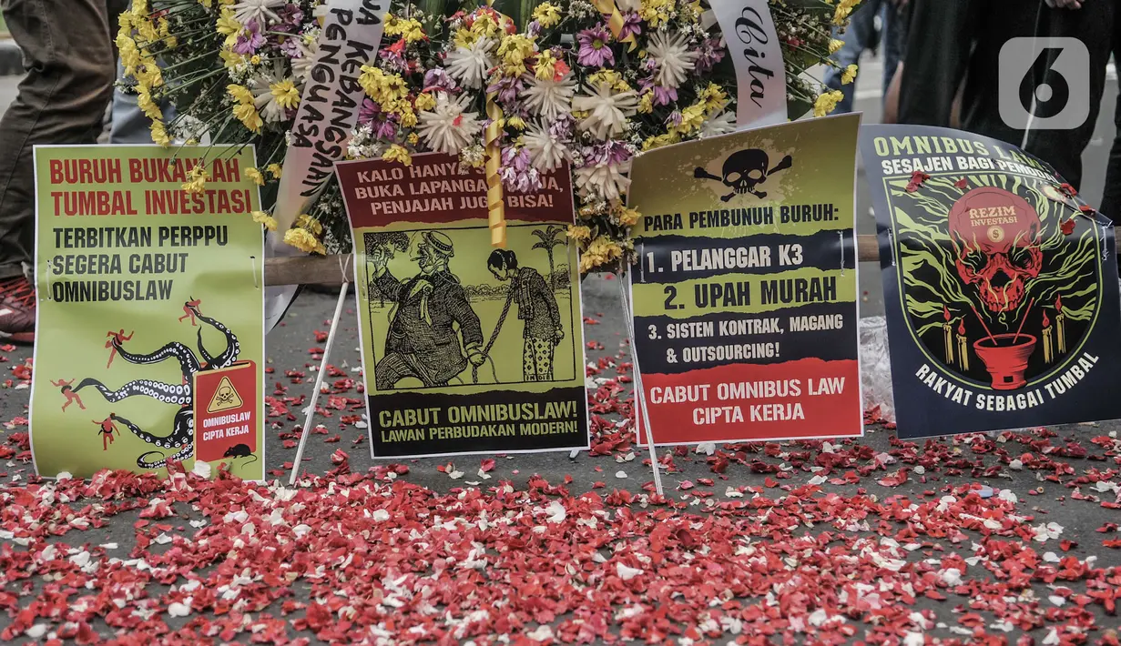 Massa buruh menaburkan bunga sebagai simbol duka atas kebijakan pemerintah di kawasan Patung Kuda, Jakarta, Senin (2/11/2020). Buruh dari berbagai serikat pekerja menggelar demo terkait penolakan pengesahan omnibus law Undang-Undang Cipta Kerja dan upah minimum 2021. (merdeka.com/Iqbal S Nugroho)