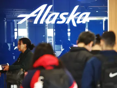 Logo Alaska Airlines ditampilkan saat pelancong berdiri di area check-in Bandara Internasional Los Angeles (LAX) di Los Angeles, California, Senin (8/1/2024). (Mario Tama/Getty Images/AFP)