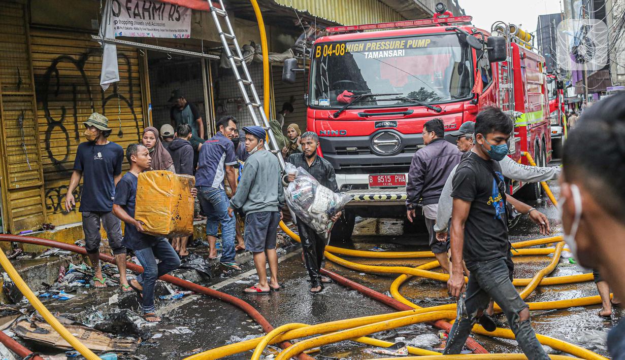 Pedagang menyelamatkan barang dagangan saat proses pendinginan oleh damkar dari kebakaran di Pasar Pagi Asemka, Jakarta, Jumat (18/11/2022). Dugaan penyebab sementara, berdasarkan informasi awal dari lokasi terjadi korsleting listrik," sebut Joko. (Liputan6.com/Faizal Fanani)