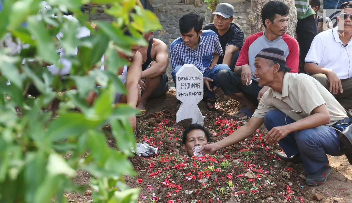 Warga yang tergabung dalam Aliansi Tanah Untuk Rakyat melakukan aksi kubur diri di Taman Kayu Mas, Pulogadung, Jakarta Timur, Jumat (23/8/2019). Mereka menuntut  BPN Jakarta Timur mempercepat proses pengukuran dan melawan mafia tanah. (Liputan6.com/Herman Zakharia)