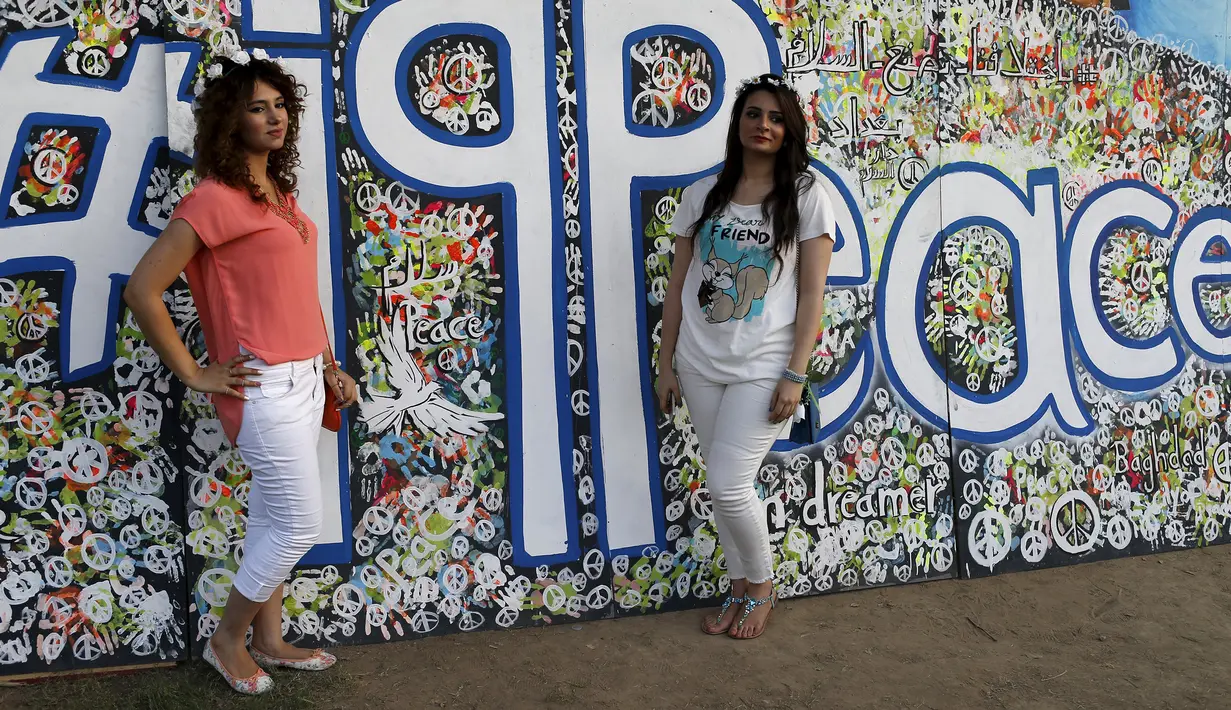 Dua gadis cantik berpose di depan lukisan abstrak saat mengunjungi festival memperingati Hari Perdamaian Internasional di Baghdad, Irak (21/9/2015). Perayaan diisi dengan kreativitas seni karya para pemuda dan pemudi Irak. (REUTERS/Thaier al-Sudani)