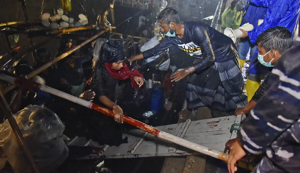 Pria Rohingya membantu orang lain untuk turun dari perahu mereka setibanya di Pelabuhan Krueng Geukueh di Aceh Utara, Indonesia, Jumat (31/12/2021). Sedikitnya 120 orang etnis Rohingya yang sempat terombang-ambing di lautan selama beberapa hari akhirnya dievakuasi ke daratan Aceh. (AP Photo/Rahmat M